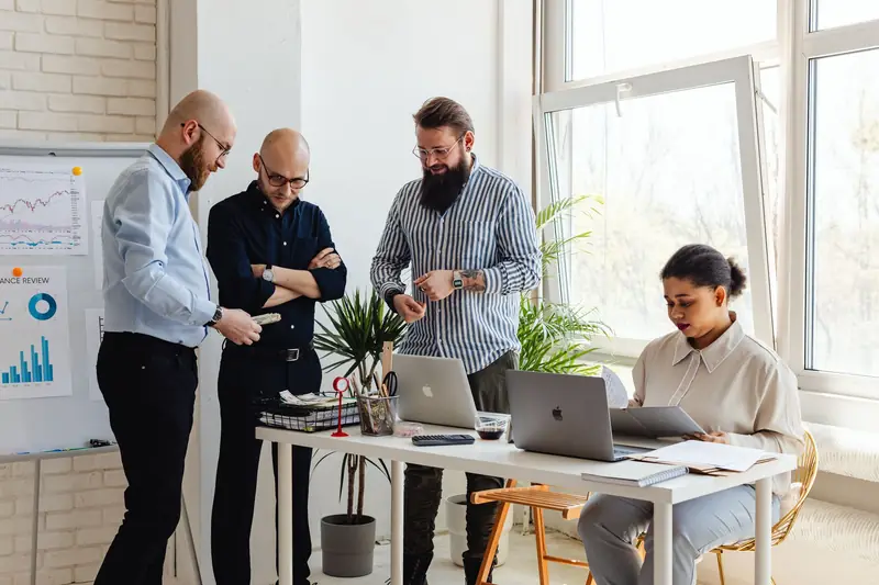 Klein team overlegt rond een bureau met laptops in een licht kantoor