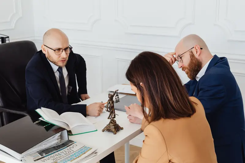 Adviseur bespreekt documenten met klanten aan zijn bureau